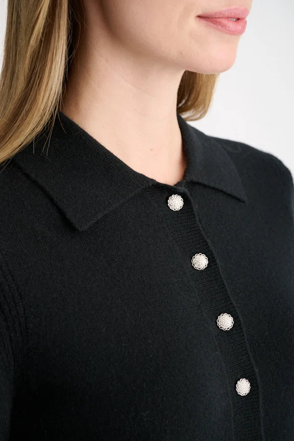 Close-up of the crystal button placket on a black cashmere polo sweater.