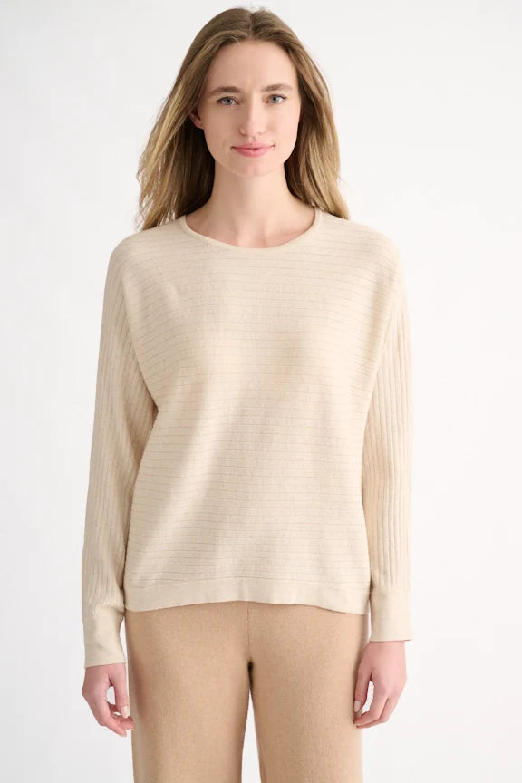 Front view: Woman wearing a beige horizontal rib knit pullover with tan trousers