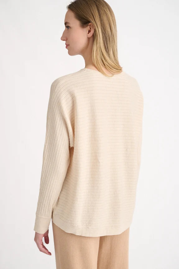 Back view: Back view of a beige horizontal rib knit pullover showing ribbed sleeve detail