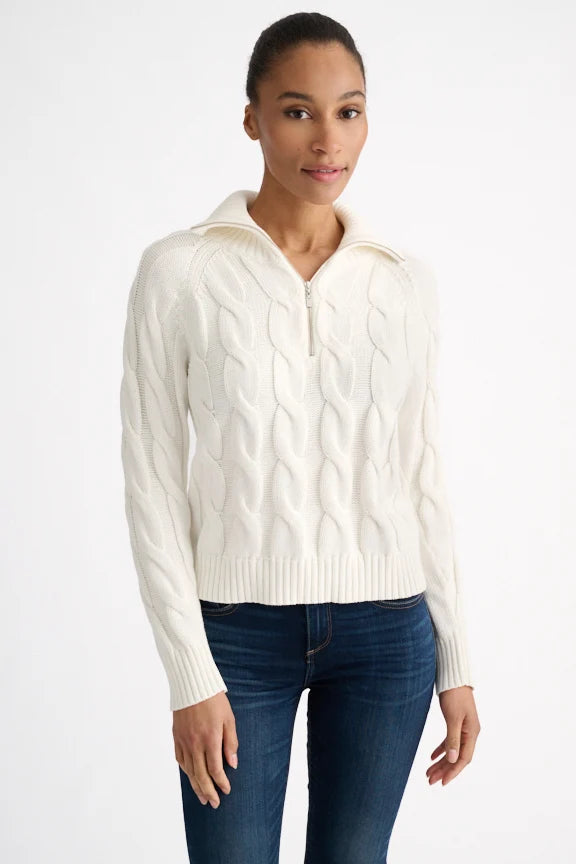 Woman wearing a cream cable knit zip mock neck sweater over jeans.
