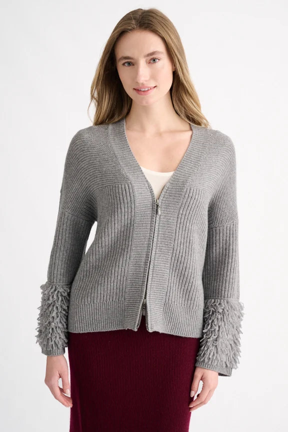 Woman wearing a granite grey shaker-rib cardigan with fringe cuff detail and a burgundy knit skirt.