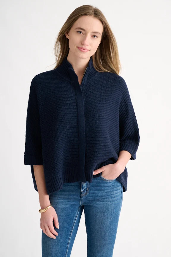 Woman wearing a navy rib knit wool-cashmere cardigan with a mock zip neckline and 3/4 sleeves, paired with jeans.