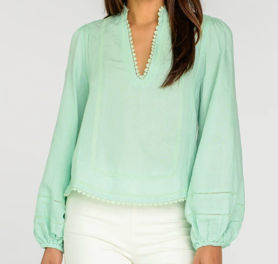 Light green blouse with long sleeves and a V-neckline on a plain background