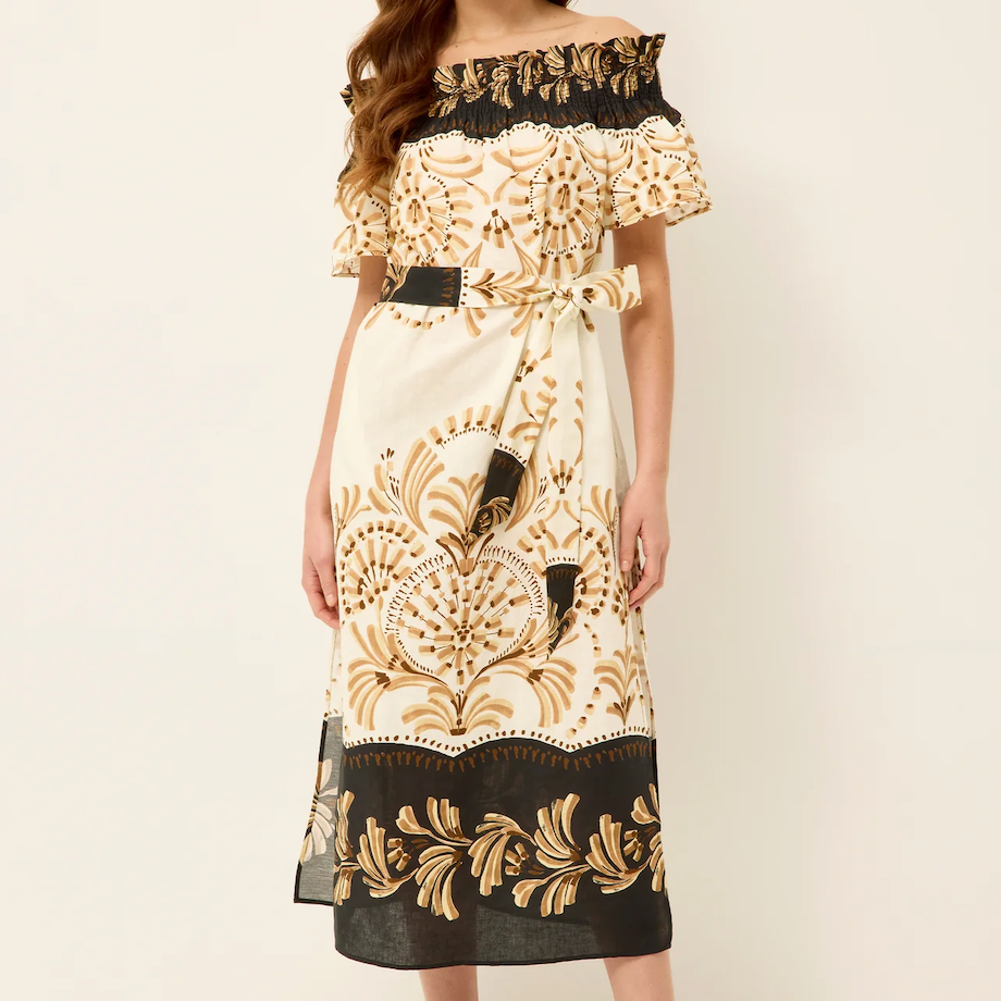 Woman wearing a black and gold patterned dress on a white background