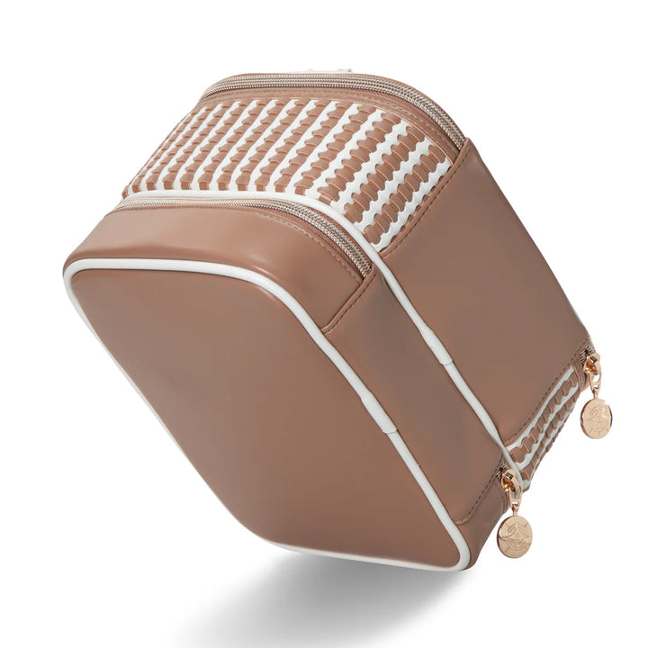 Three-quarter angled view: Stephanie Johnson Jenny Train Case in Marbella colorway, angled to show woven top panel transitioning to solid tan side panel, white piping, and dual rose gold zipper pulls with engraved charms.