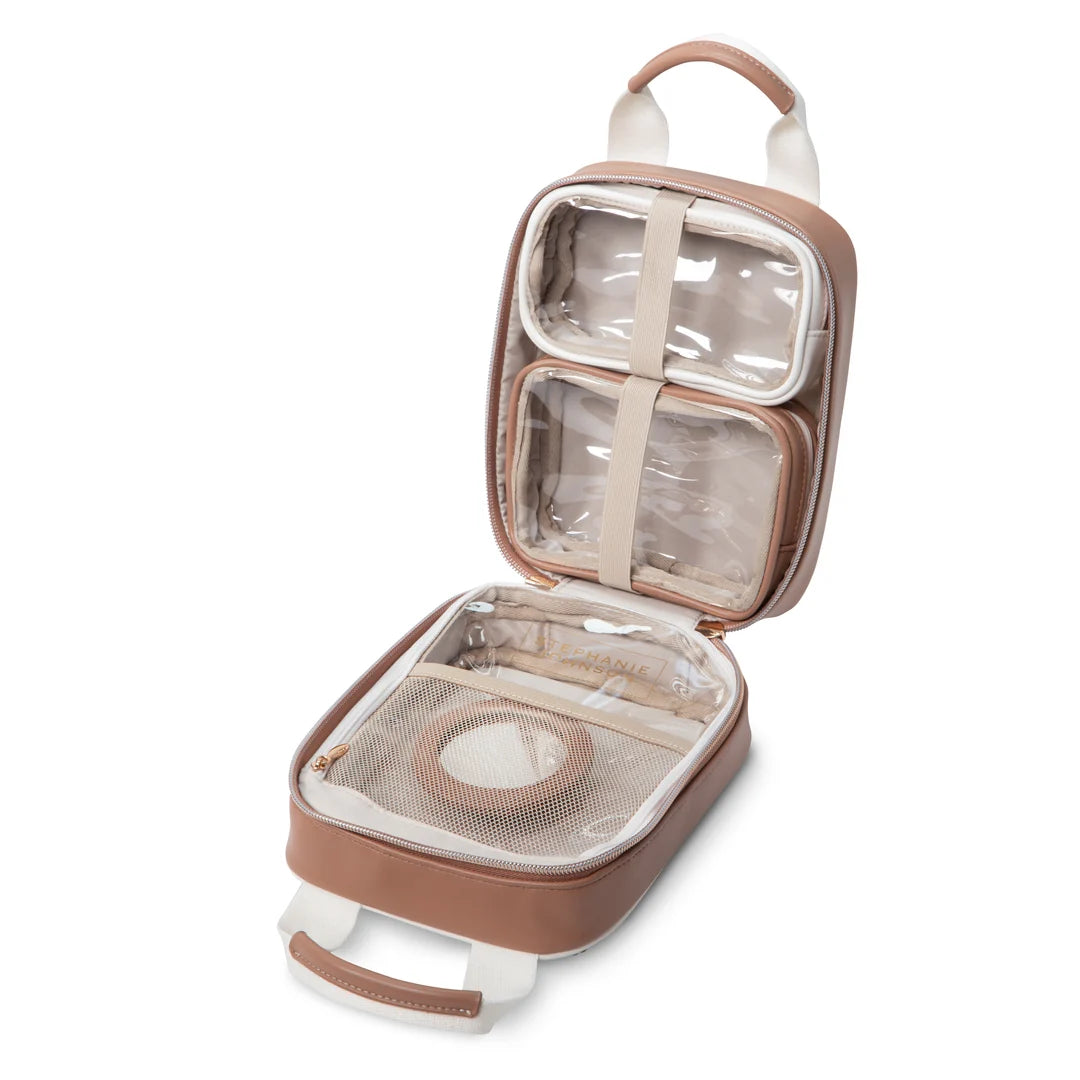 Open/interior view: Stephanie Johnson Sasha Travel Bag shown open, highlighting two clear-topped compartments held by elastic straps, zippered mesh brush pocket, and tan interior lining with brand nameplate.