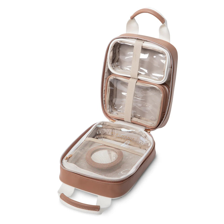 Open/interior view: Stephanie Johnson Sasha Travel Bag shown open, highlighting two clear-topped compartments held by elastic straps, zippered mesh brush pocket, and tan interior lining with brand nameplate.