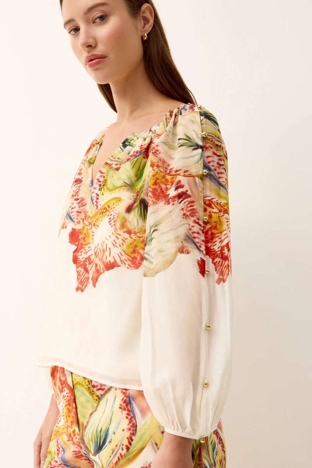 Marie Oliver Arabella Blouse in ivory silk with Sonnet botanical placement print, gathered neckline, and gold button sleeve detail. - side pose