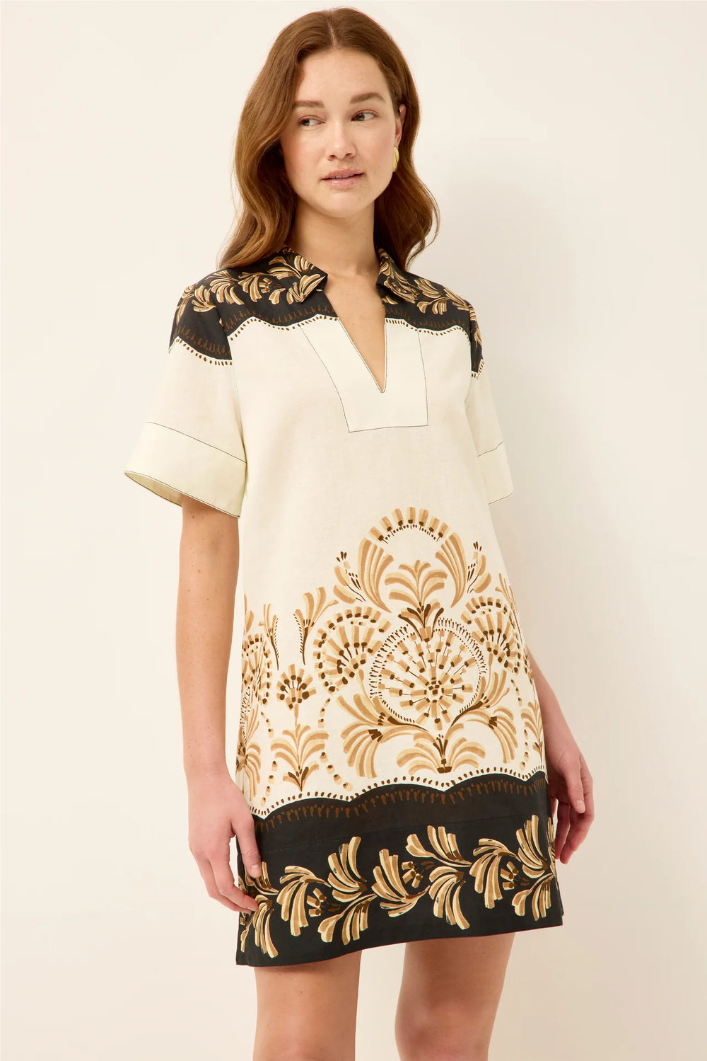 Marie Oliver Dede Dress in Fleuron — three-quarter front view highlighting the engineered border print, V-notch neckline, and straight relaxed silhouette at mini length.