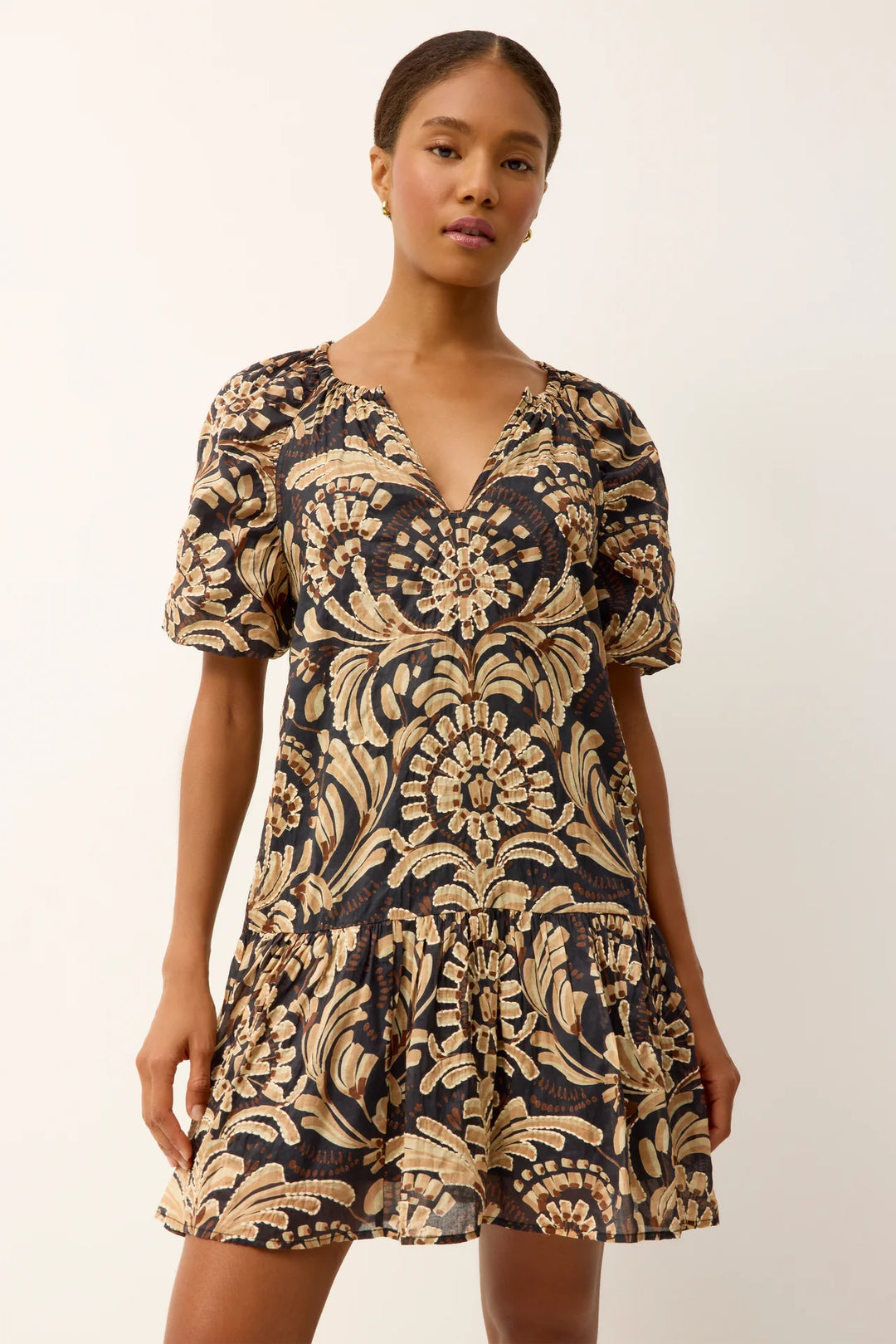 Marie Oliver Greta Tropez Dress in dark navy and gold medallion print — close-up front on-model view, smocked V-neckline and puff sleeve detail with bold tapestry-style floral motif