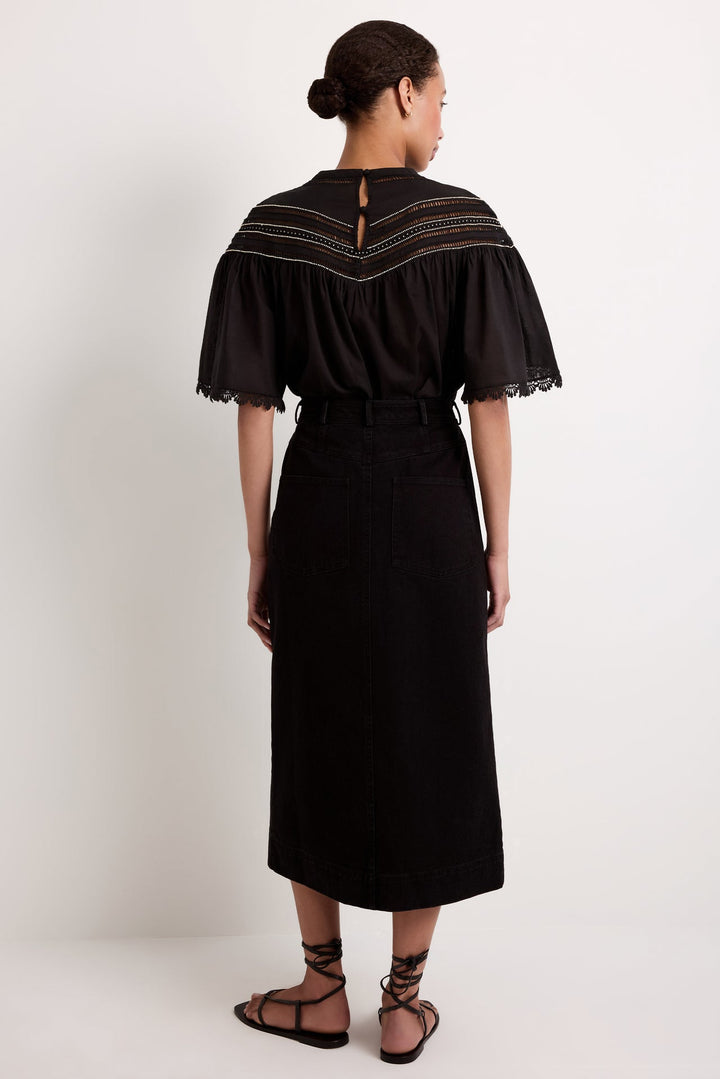 Marie Oliver Leighton Denim Skirt in Pavement, full-length back view on model, showing back patch pockets, center back seam, and straight midi hem