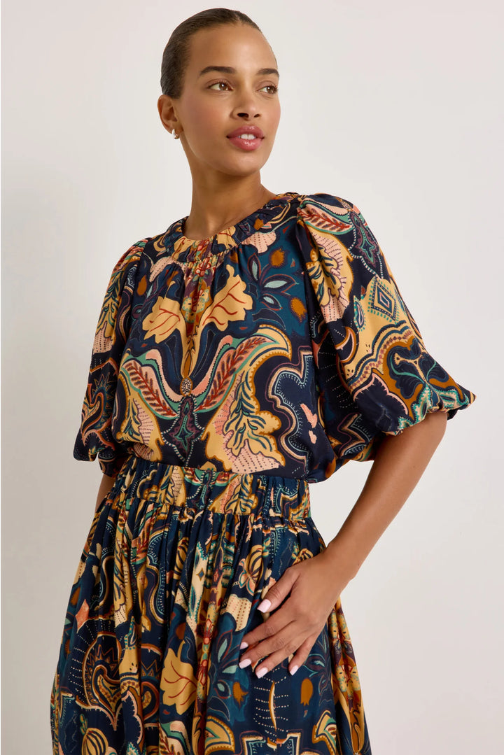 Marie Oliver Wren Top in Saddle, front three-quarter view on model, showing the gathered crew neckline and voluminous puff sleeves in a navy, ochre, teal, and blush botanical print