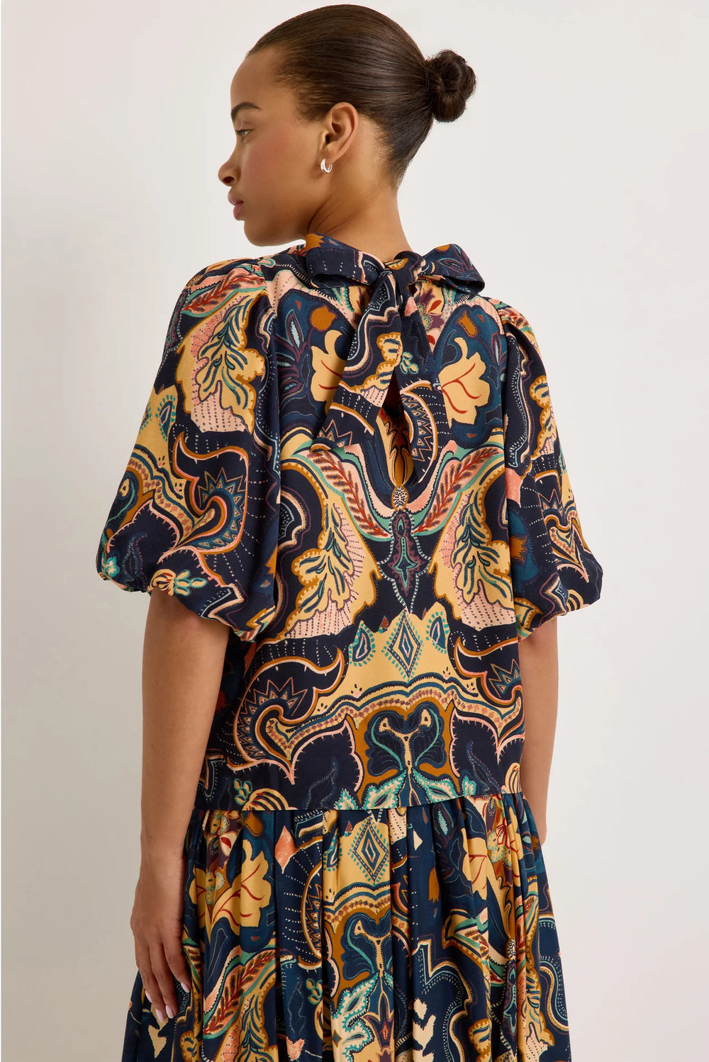 Marie Oliver Wren Top in Saddle, back view on model, showing the keyhole opening with self-tie bow at the nape and puff sleeves gathered at the elbow