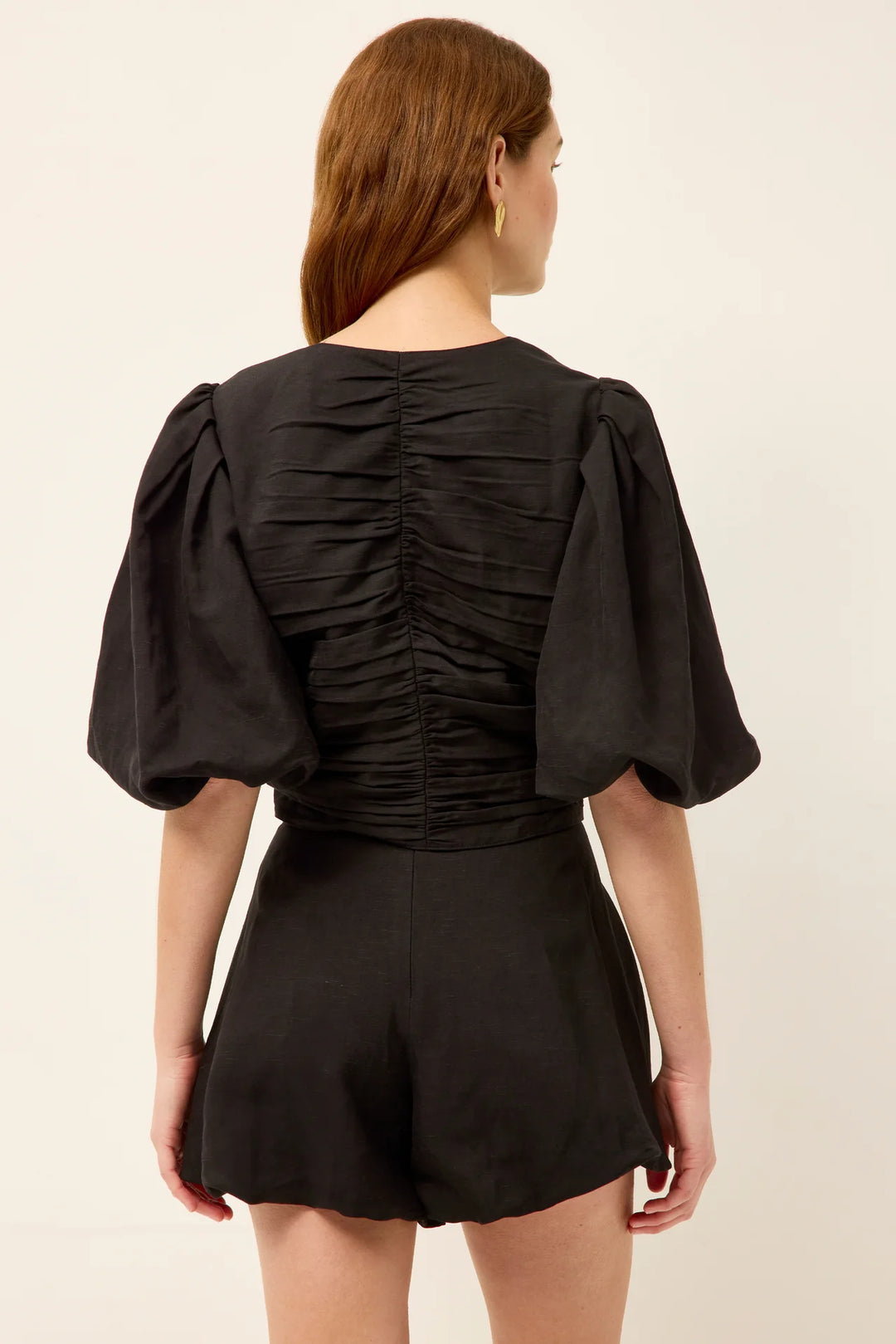 Marie Oliver Rowan Top in Black — back view showing full-length ruching detail down center back, voluminous puff sleeves, and cropped silhouette on model.
