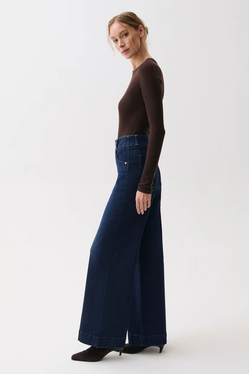 Side profile view of the wide-leg denim silhouette from waist to hem.