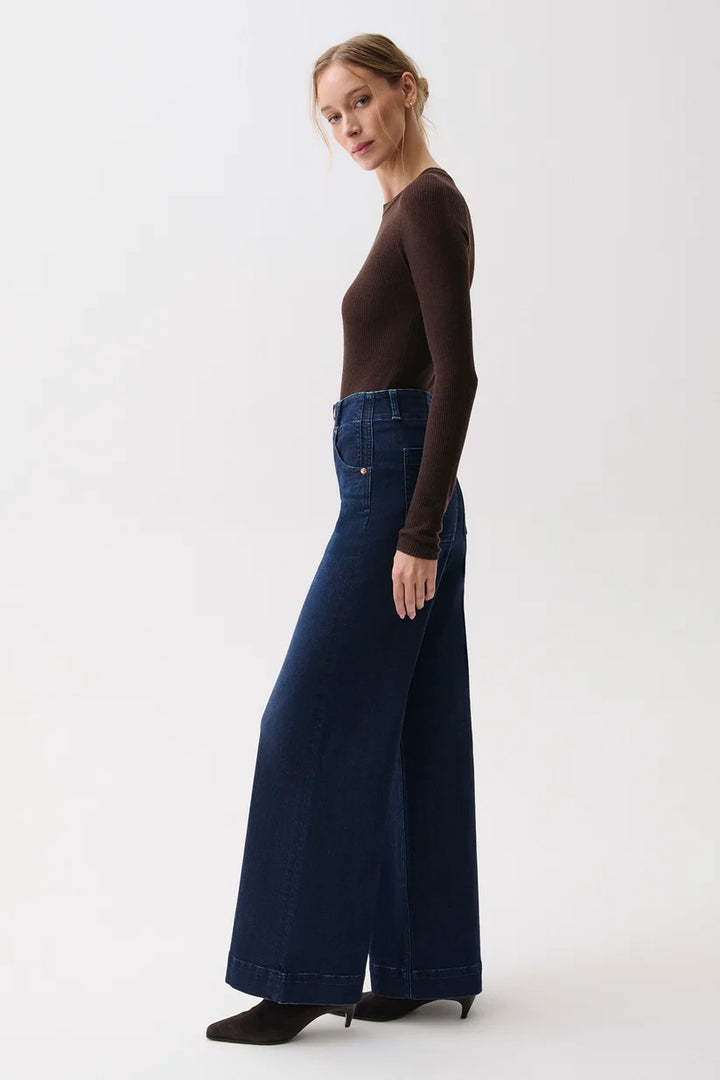 Side profile view of the wide-leg denim silhouette from waist to hem.