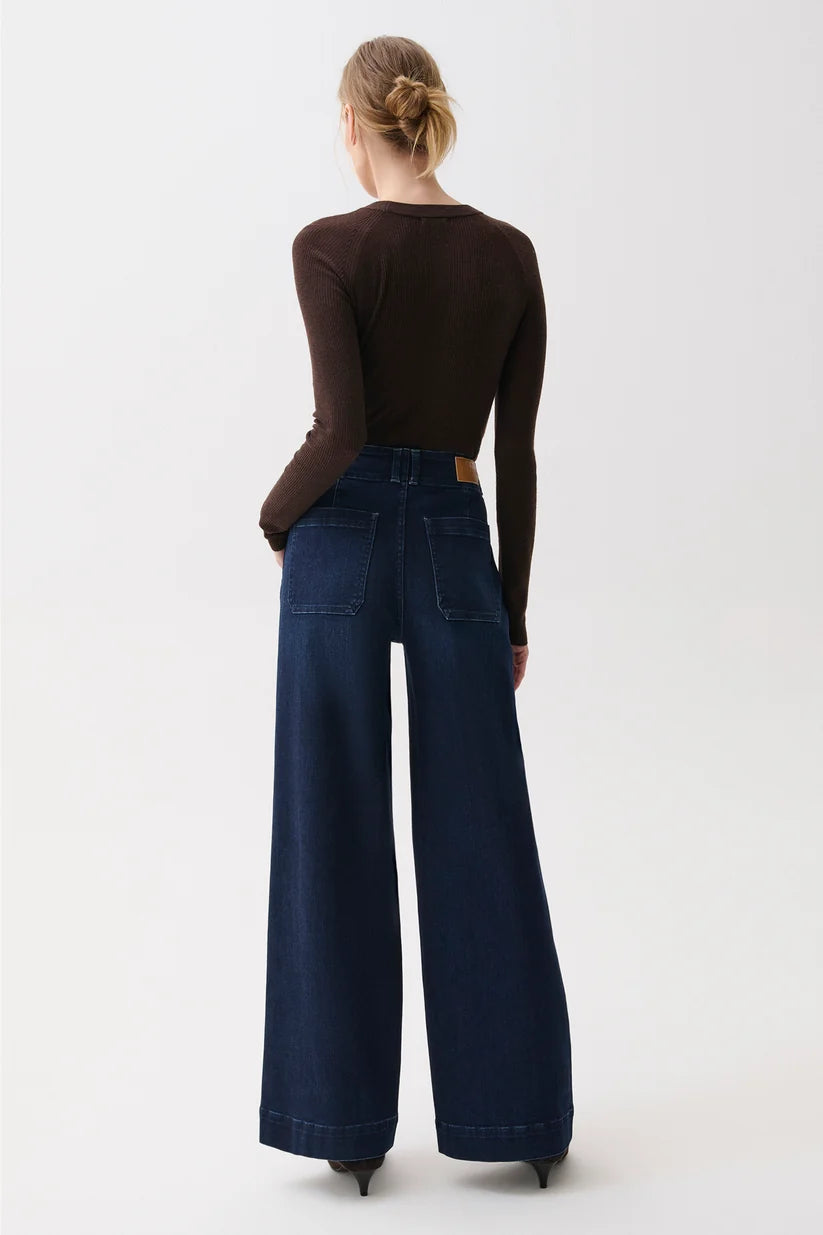 Back view showing patch pockets and wide-leg drape of the dark wash denim.