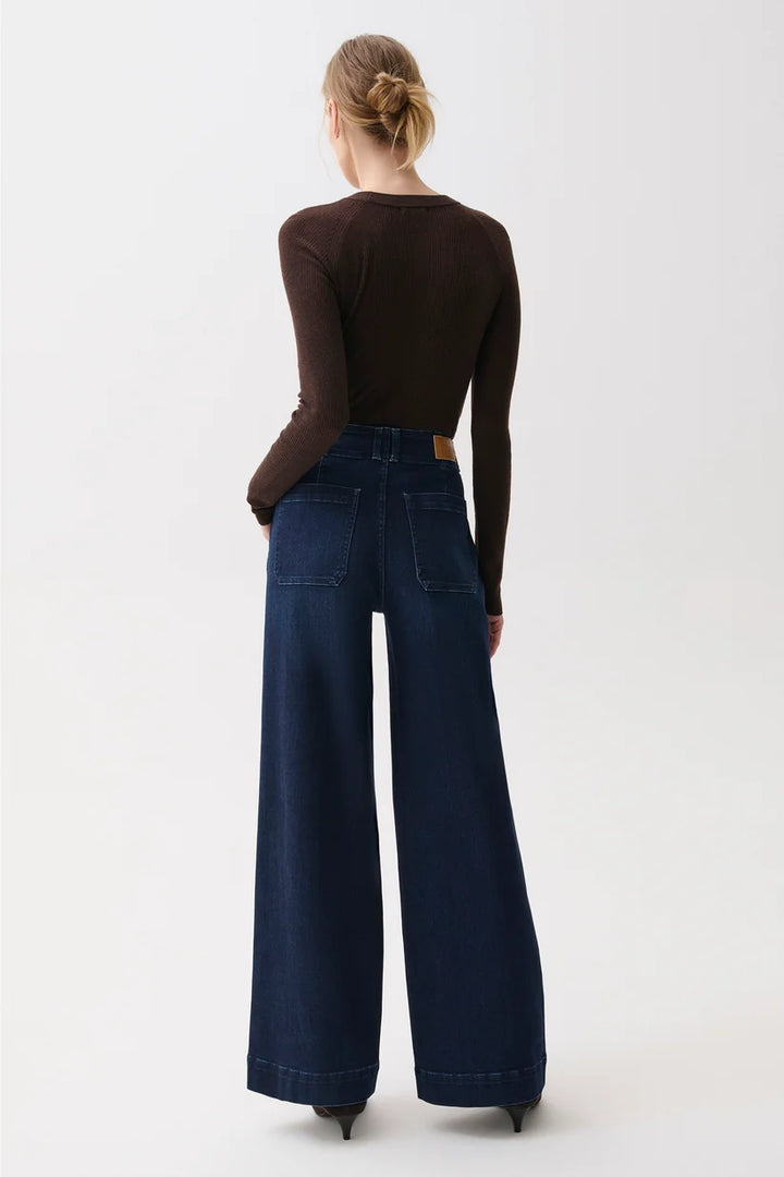 Back view showing patch pockets and wide-leg drape of the dark wash denim.