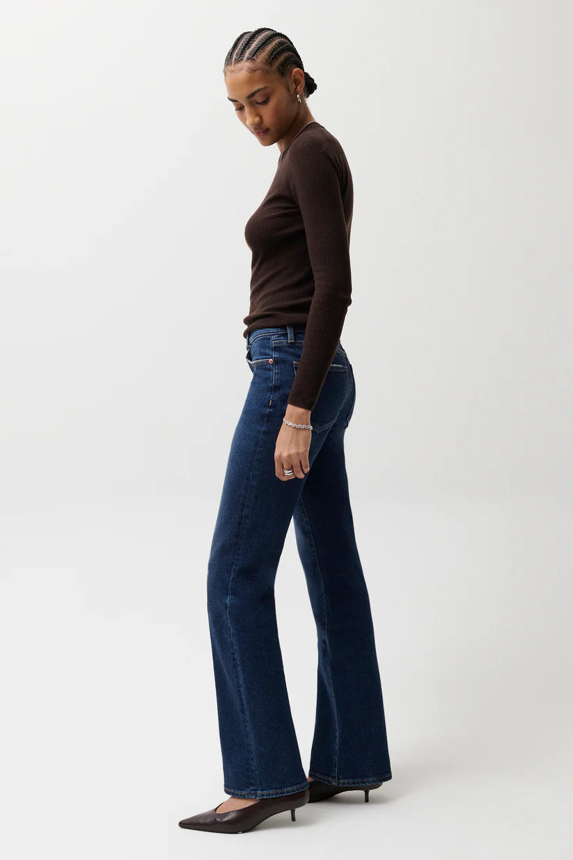 Pistola Evie High Rise Slim Boot Jean in Penthouse, dark indigo denim, side view showing slim hip and flared bootcut leg, styled with brown ribbed top and heels