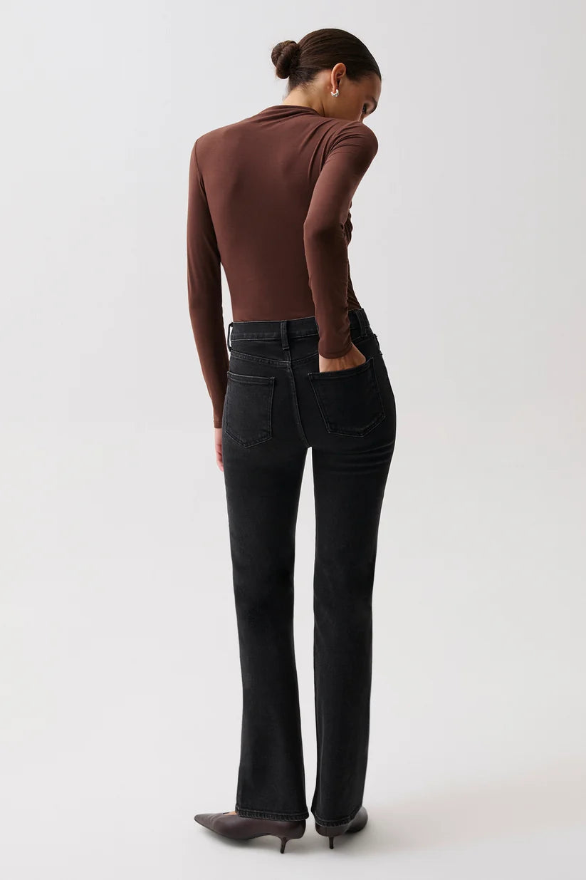 Pistola Evie High Rise Slim Boot in Jetset, three-quarter side view of lower body, showing high-rise waistband, five-pocket front, washed black finish, and gentle flare through the calf.