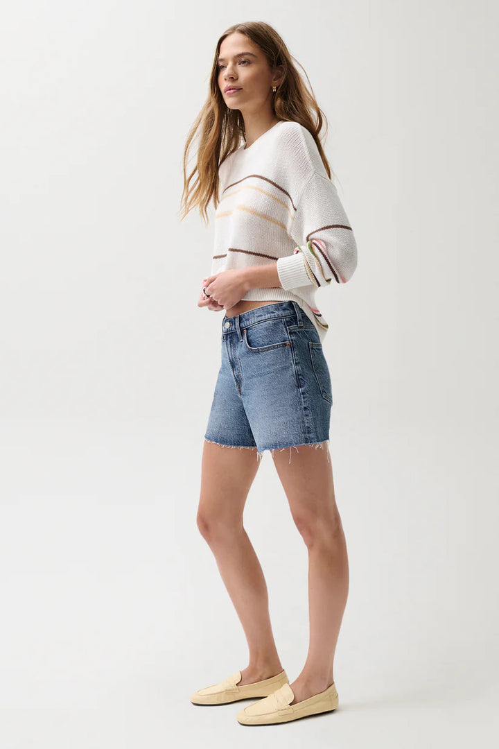 Pistola Kennedy Mid Rise Short in Cityscape, medium-wash denim, mid rise fit with raw-cut hem and relaxed leg, styled with striped cream knit and loafers