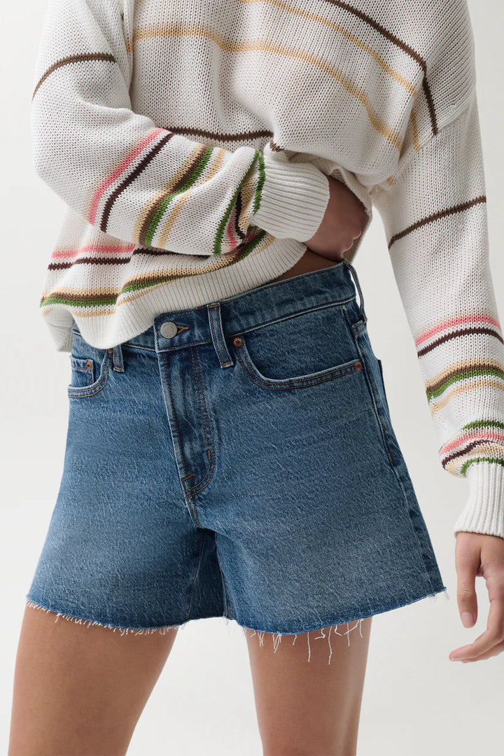 Pistola Kennedy Mid Rise Short in Cityscape, close-up of mid rise waistband, five-pocket construction, and raw unfinished hem in medium-wash denim