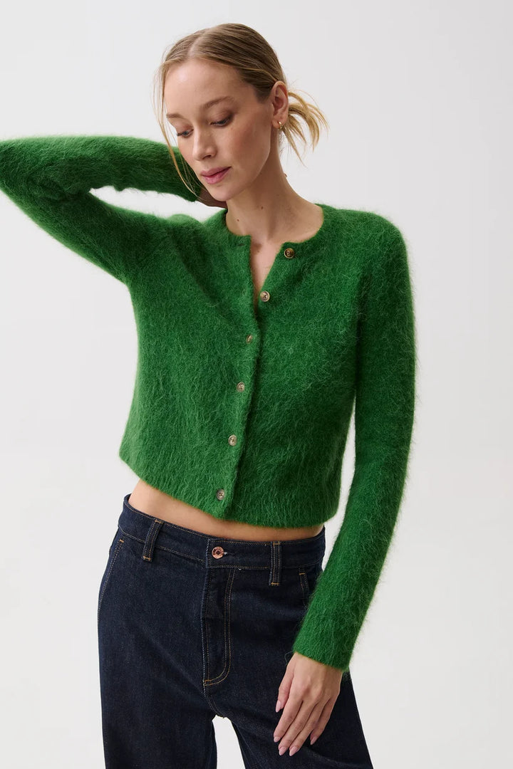 Pistola Yara Alpaca Blend Shrunken Cardigan in Vivid Moss, front view on model with one arm raised, showing brushed green knit, crew neckline, horn-look button front, and cropped length over dark rinse jeans.
