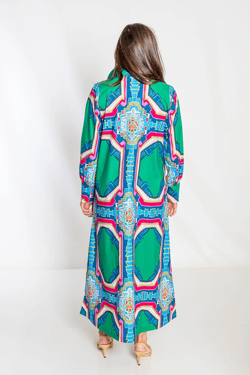 Back view: House of MBR Diana Dress Long in Portico© print shown from behind, highlighting the continuous architectural medallion pattern down the back and full maxi length, styled with nude heels.