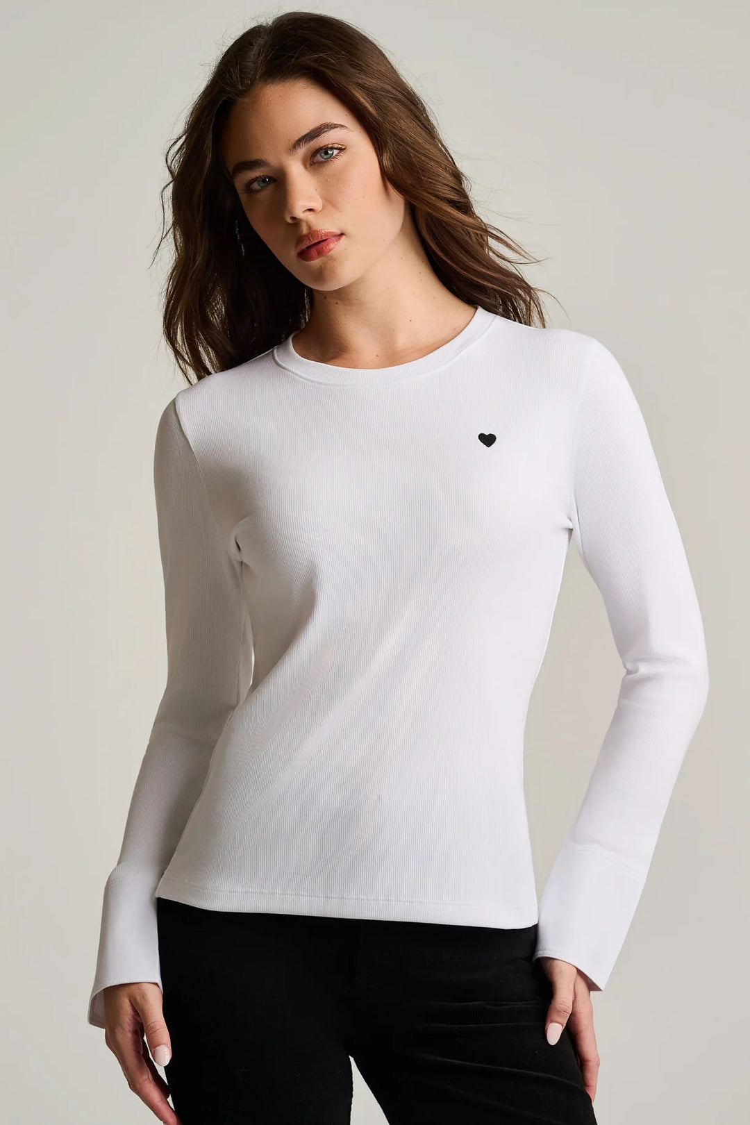 Close-up front view of a woman wearing the Pure Rib Cuff Top in white, showing the crew neckline, embroidered heart detail at the bust, and poplin button cuff.