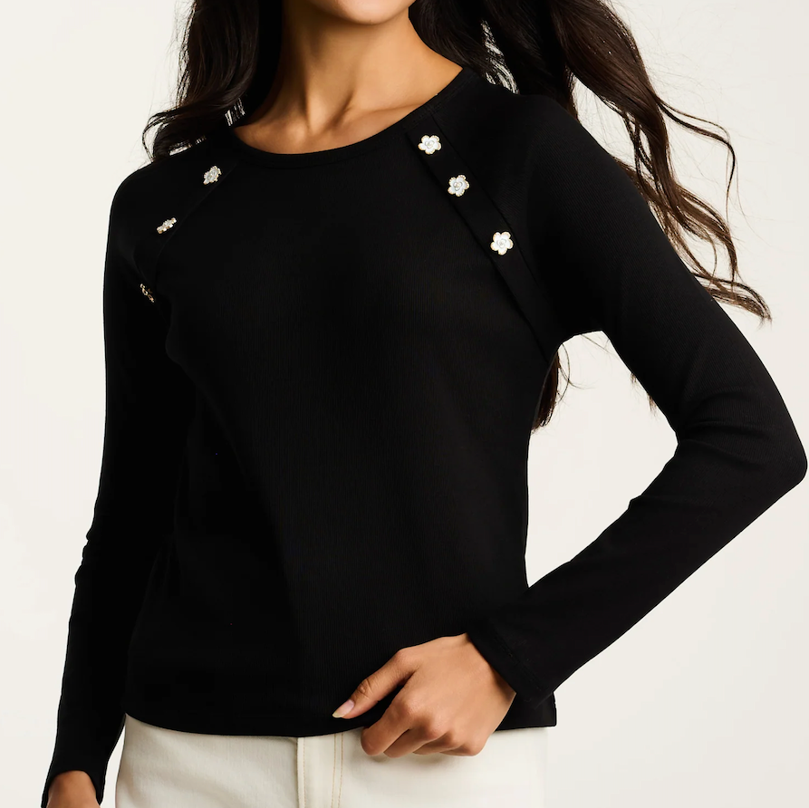 Black long-sleeve top with white floral embellishments on a plain background