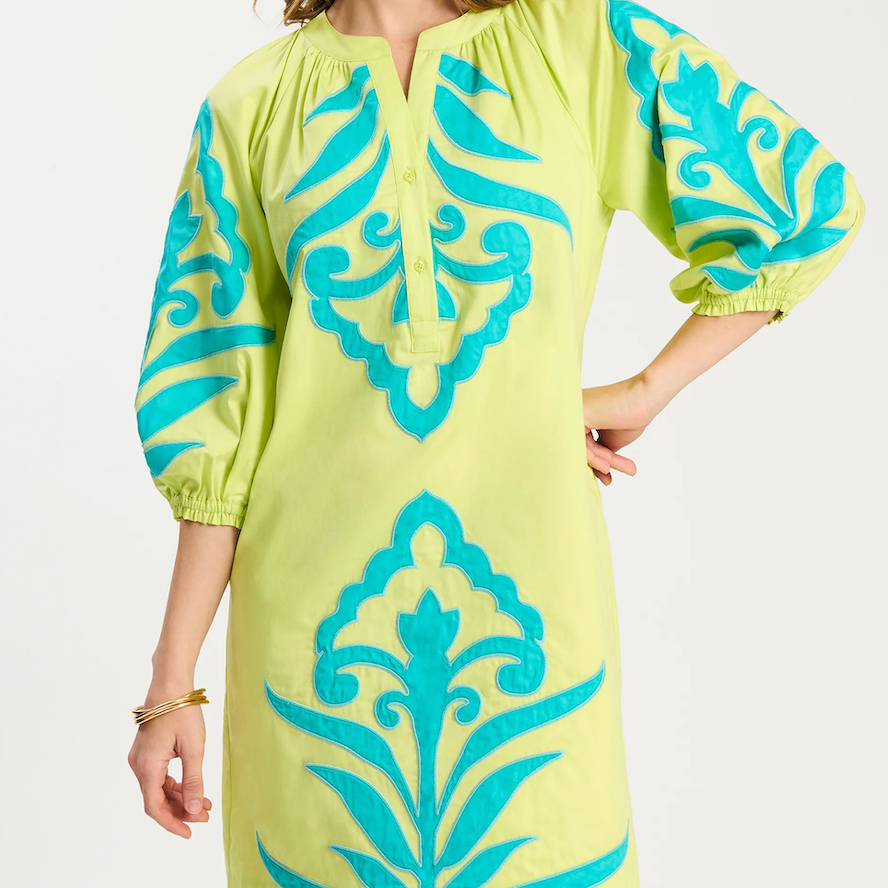 Woman wearing a yellow dress with blue floral patterns on a white background