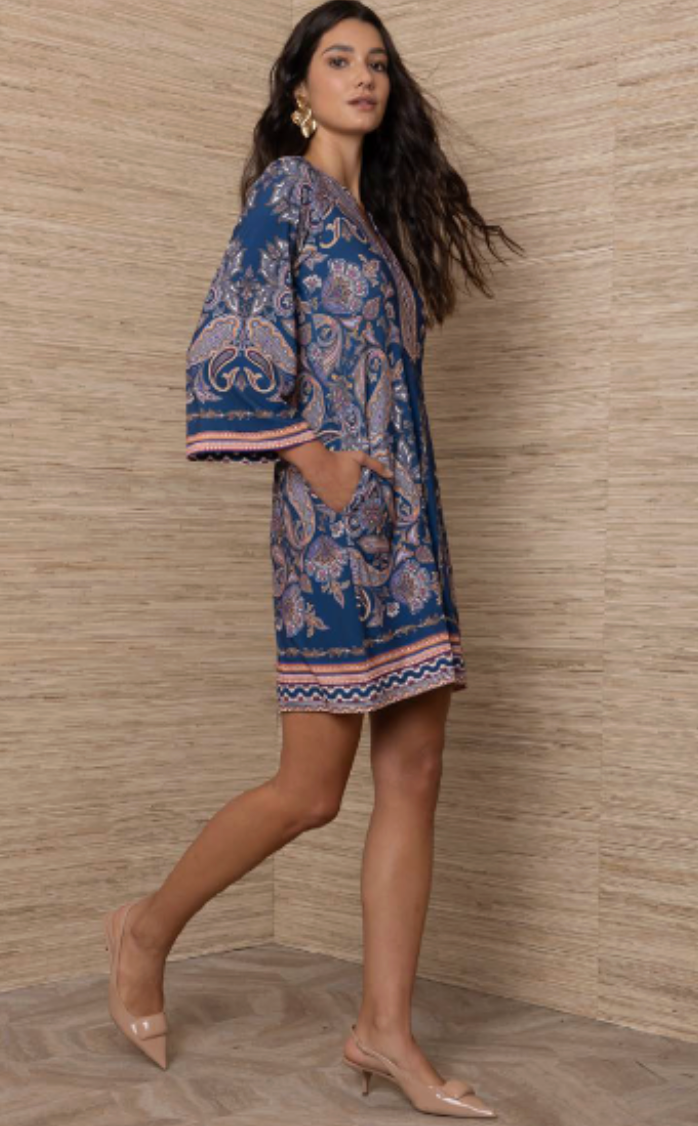 A-line paisley print shift dress with bell sleeves and border hem detail, shown on model from the side in a teal and blush colorway.