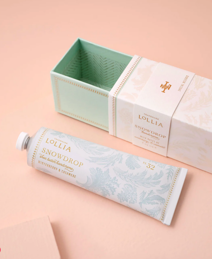 Lollia Snowdrop Handcreme tube beside its open slide-out keepsake box showing mint and gold chevron interior lining.