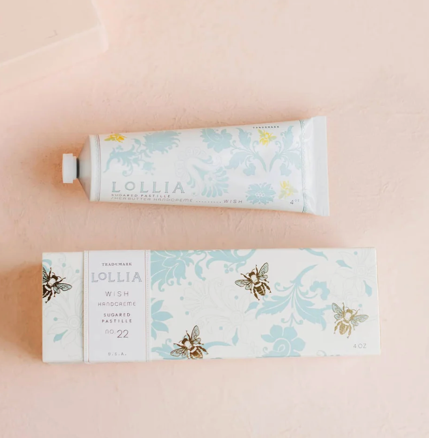 Lollia Wish Shea Butter Handcreme tube and gift box flat lay showing bee illustration and blue damask floral pattern on white ground.