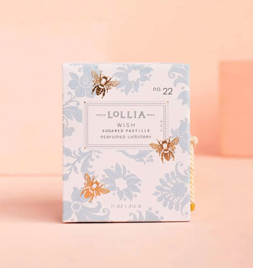 Lollia Wish Perfumed Luminary gift box with blue damask floral print, illustrated gold bees, stamp-style label, and knotted gold and ivory cord closure.