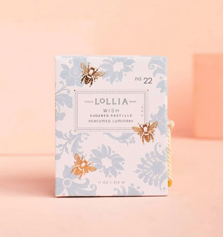 Lollia Wish Perfumed Luminary gift box with blue damask floral print, illustrated gold bees, stamp-style label, and knotted gold and ivory cord closure.