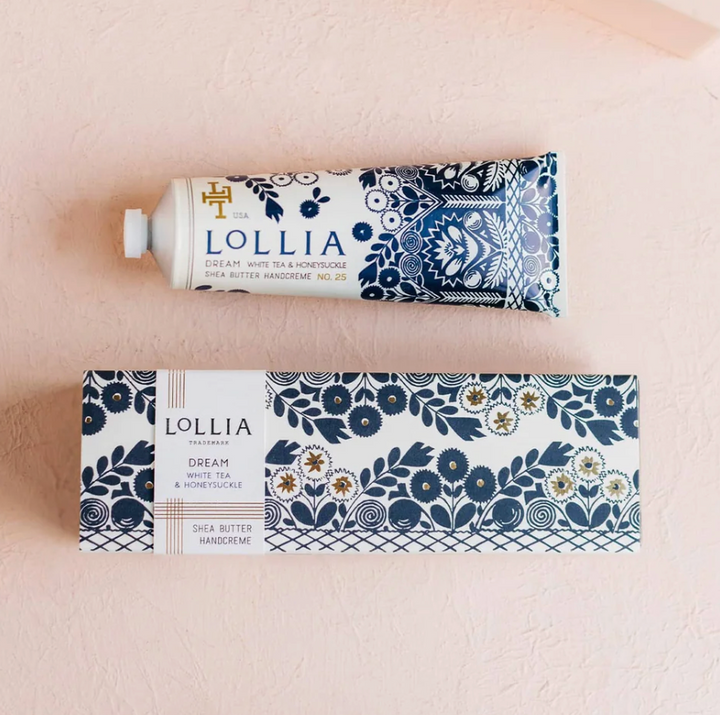 Lollia Dream Handcreme tube and gift box flat lay showing navy and white textile-inspired folk-floral print with gold accent detailing on both tube and sleeve.