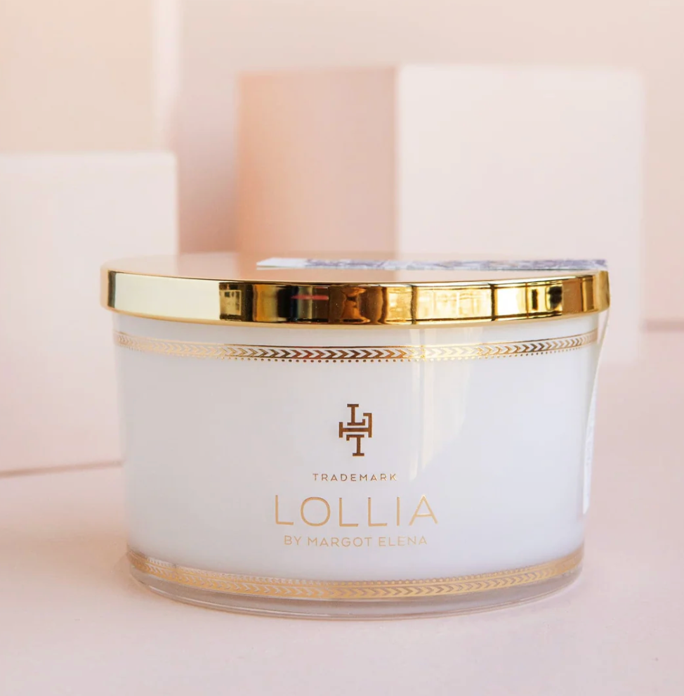 Lollia Dream Fine Bathing Salts in a white glass jar with gold reflective lid and navy folk-floral paper belly band, shown against a blush background.