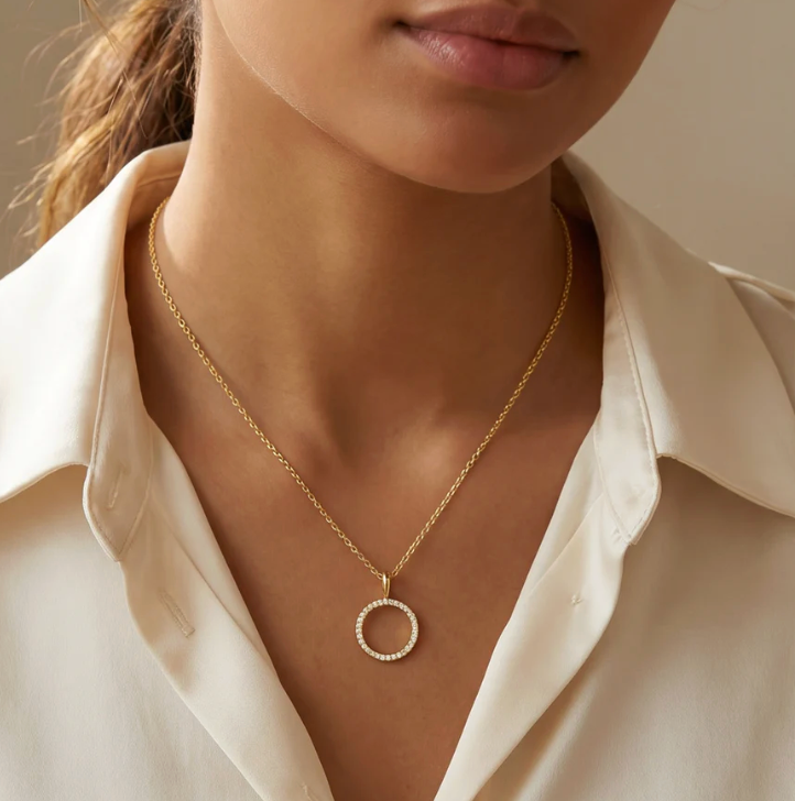 Standing O Pendant Necklace worn at collarbone length on model in cream button-down shirt, open circle diamond pendant centered at neckline, gold-tone chain