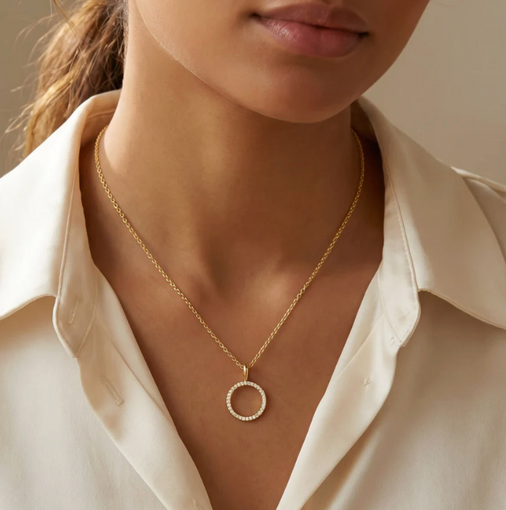 Standing O Pendant Necklace worn at collarbone length on model in cream button-down shirt, open circle diamond pendant centered at neckline, gold-tone chain