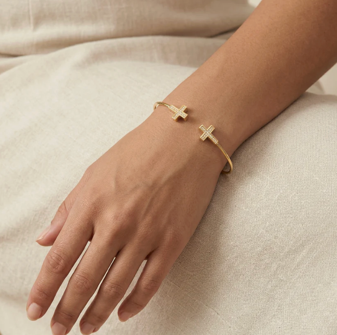 Ella Stein Cross Flexi Cuff Bracelet in gold — on-model wrist shot showing open cuff fit, cross terminal scale, and pavé diamond detail in gold plating.