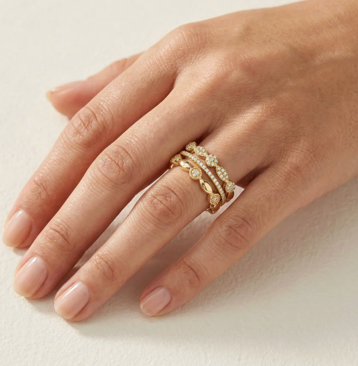 Ella Stein Shiny Three Stackable Ring Set in gold — on-model hand showing all three bands stacked on ring finger, displaying pavé half-eternity, cluster roundel, and geometric link designs together.