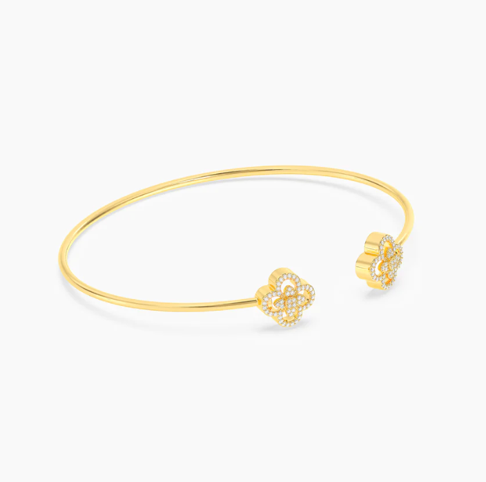 Ella Stein Wildflower Flexi Cuff Bracelet in gold — angled flat lay showing layered open-petal clover terminal construction, inner and outer pavé diamond border detail, and slim cuff profile.