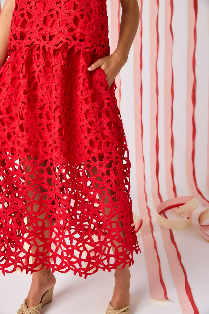 Close-up of Crosby Selene Lace Skirt in Pomegranate showing all-over geometric crochet lace construction, lined upper skirt transitioning to open unlined lace hem border, and side seam pocket.