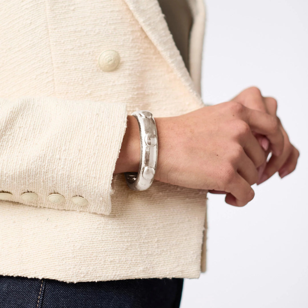 Julie Vos Solara Hinge Bangle in silver plate with hammered finish, dome stud accents, and engraved interior lattice pattern on model.