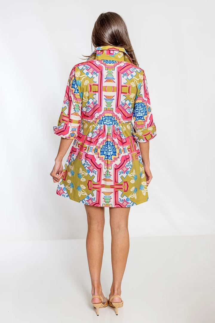 Back view: House of MBR Blythe Dress Short in Surcie© print shown from behind, highlighting the mirrored ornamental pattern across the back bodice and gathered skirt, styled with nude heels.