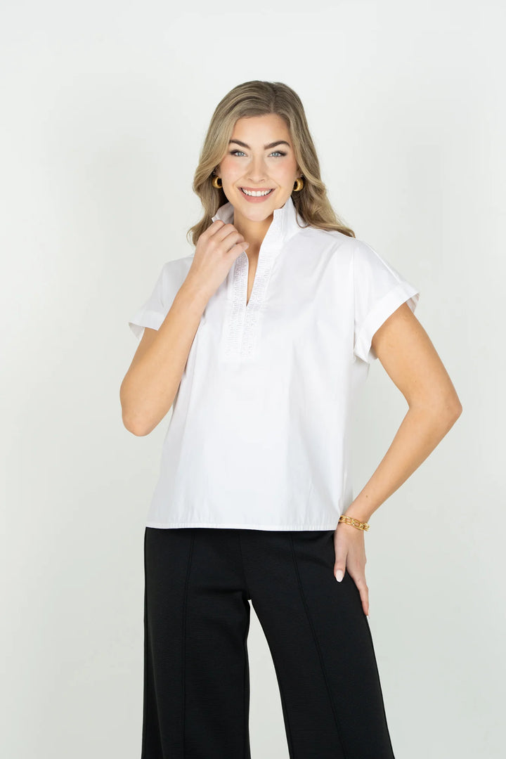Emily McCarthy Riviera Top in White — front on-model, hand at collar, styled with black wide-leg trousers and gold jewelry