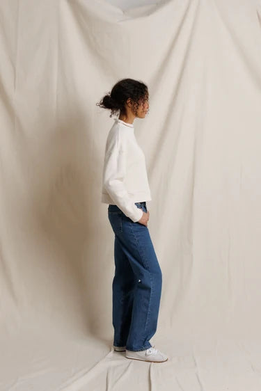 Side profile view of the model wearing the cropped, boxy sweatshirt with jeans and white sneakers.