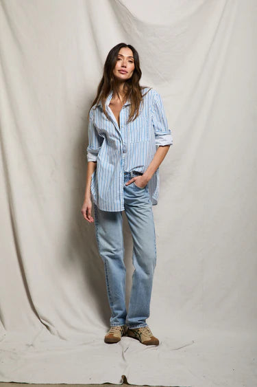 On-Model, Front
Woman wearing blue and white stripe oversized cotton poplin button-down shirt open over white tank, half-tucked into light-wash straight-leg denim, styled with tan sneakers, neutral studio backdrop — perfectwhitetee Avalon Shirt