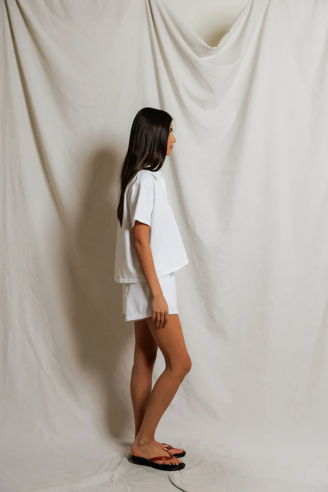 Side view of white cropped polo top showing boxy silhouette and relaxed short sleeve, paired with white mini shorts and flip sandals — perfectwhitetee Charlie Tennessee Jersey Polo